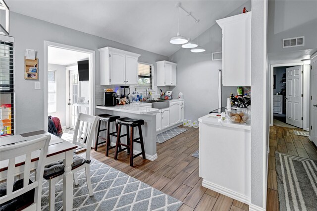 kitchen with a breakfast bar, sink, vaulted ceiling, decorative backsplash, and white cabinets