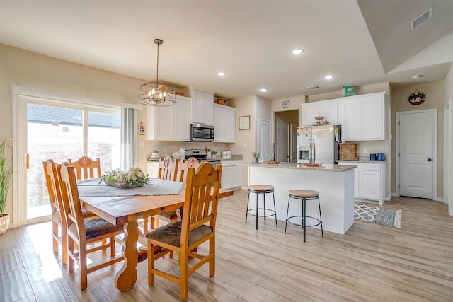 dining area featuring lofted ceiling, a chandelier, and light hardwood / wood-style flooring