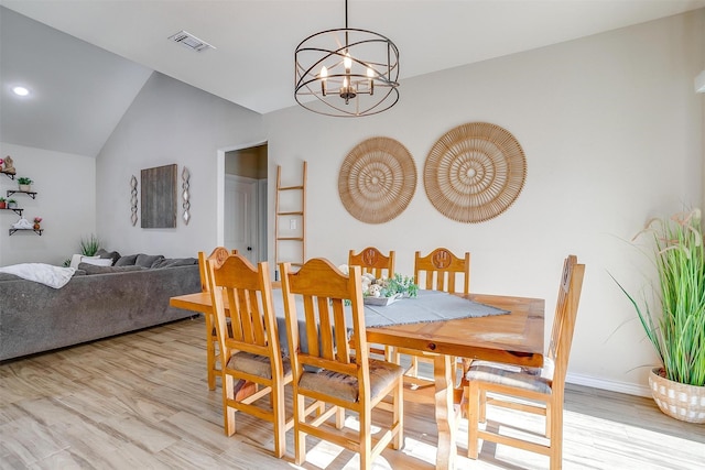 dining area with light wood-type flooring, lofted ceiling, and an inviting chandelier