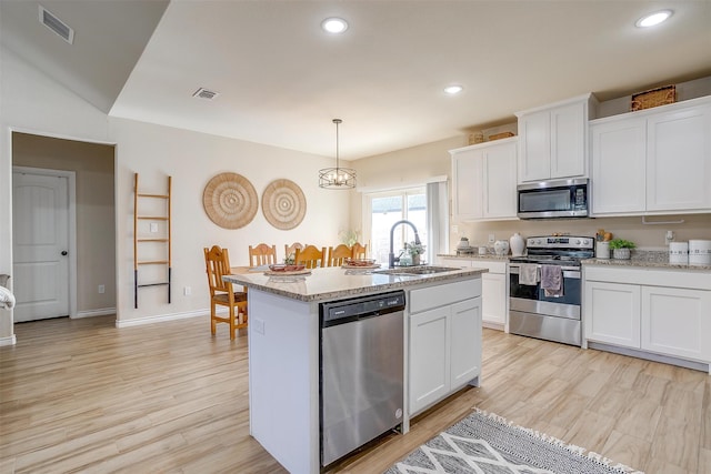 kitchen featuring stainless steel appliances, a kitchen island with sink, decorative light fixtures, white cabinets, and sink