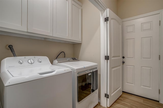 laundry room with cabinets, light hardwood / wood-style flooring, and washing machine and dryer