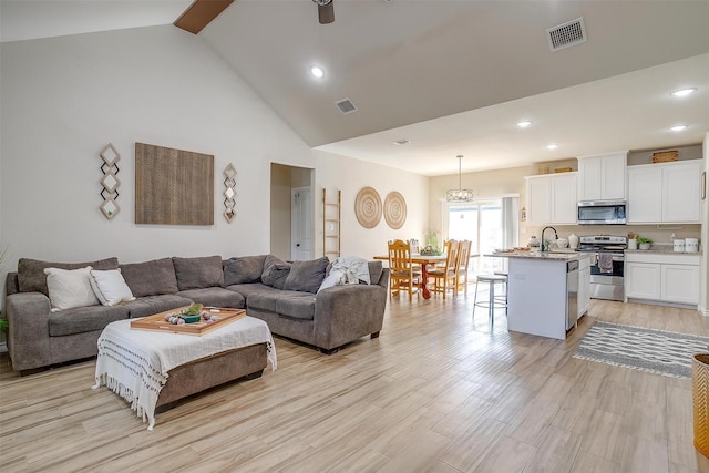 living room with light hardwood / wood-style floors, sink, high vaulted ceiling, and ceiling fan