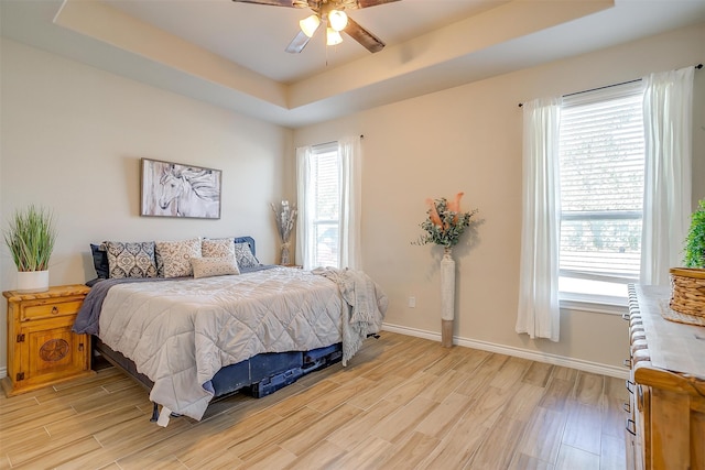 bedroom featuring a raised ceiling, ceiling fan, and light hardwood / wood-style floors