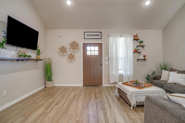 living room featuring lofted ceiling and light hardwood / wood-style flooring