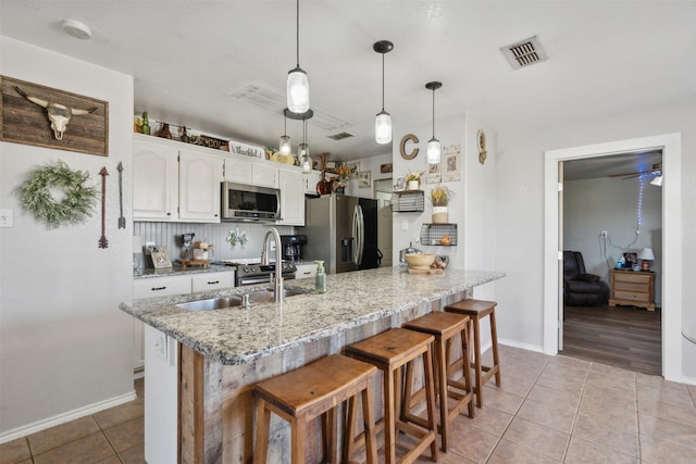 kitchen with pendant lighting, sink, appliances with stainless steel finishes, white cabinetry, and light tile patterned flooring