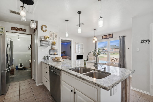 kitchen featuring sink, appliances with stainless steel finishes, pendant lighting, a kitchen island with sink, and white cabinets