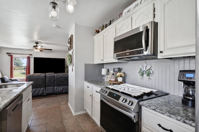 kitchen featuring white cabinetry, sink, dark tile patterned flooring, and appliances with stainless steel finishes