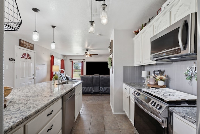 kitchen featuring pendant lighting, sink, appliances with stainless steel finishes, white cabinets, and tile patterned floors