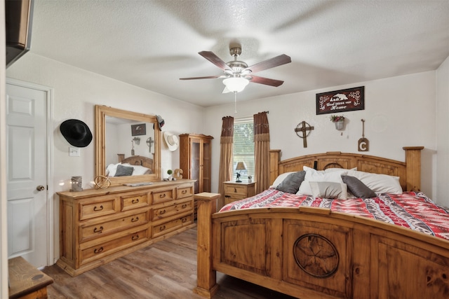 bedroom with ceiling fan, light hardwood / wood-style floors, and a textured ceiling