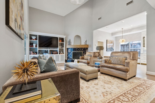 living room with light hardwood / wood-style floors, a high ceiling, and a fireplace