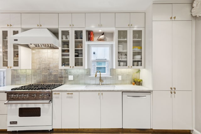 kitchen with custom exhaust hood, designer stove, sink, white cabinets, and dishwashing machine