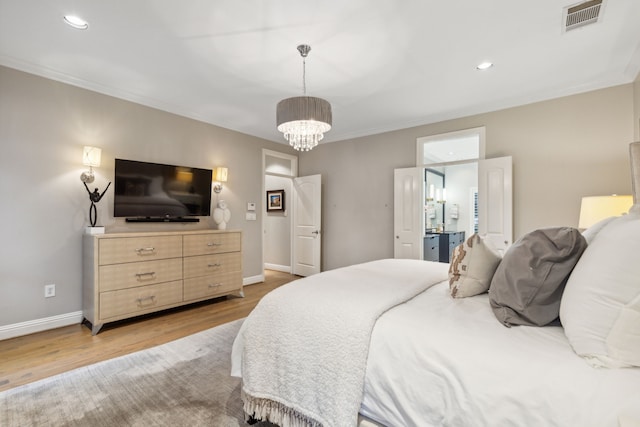 bedroom with ensuite bathroom, light hardwood / wood-style flooring, and an inviting chandelier