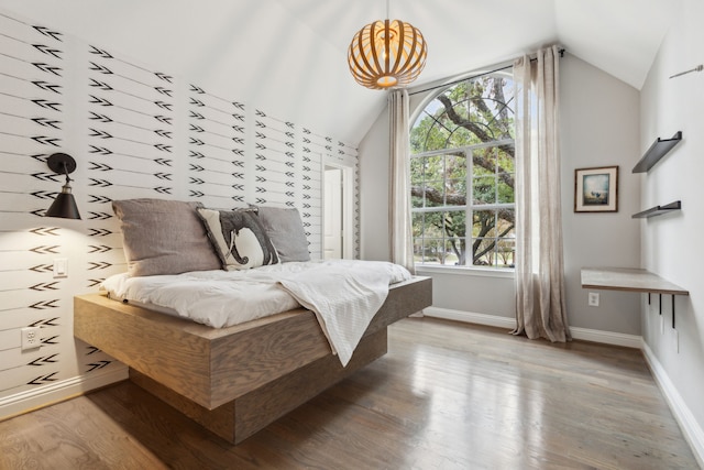 bedroom featuring multiple windows, lofted ceiling, and light wood-type flooring