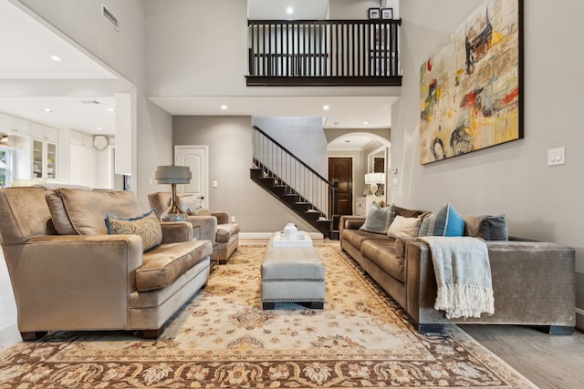 living room with hardwood / wood-style floors, crown molding, and a towering ceiling