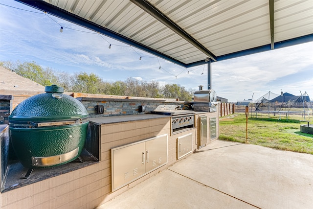 view of patio with an outdoor kitchen, a grill, and a trampoline