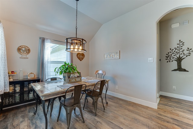 dining area with hardwood / wood-style flooring, lofted ceiling, and an inviting chandelier