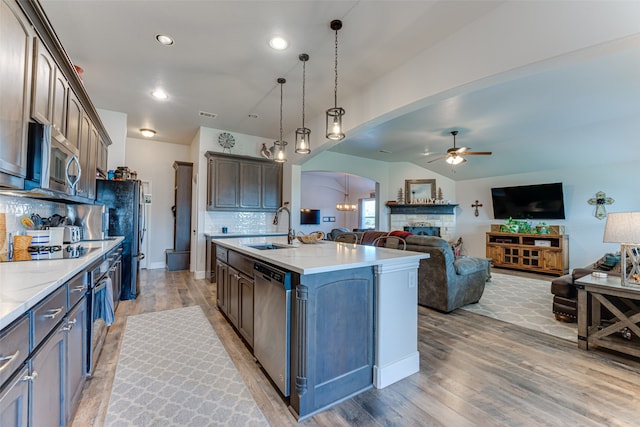 kitchen featuring decorative light fixtures, sink, a kitchen island with sink, dark brown cabinetry, and stainless steel appliances