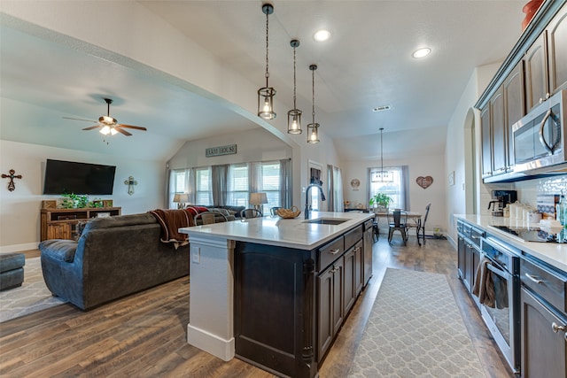 kitchen with dark brown cabinetry, sink, a center island with sink, pendant lighting, and stainless steel appliances