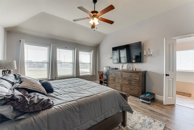 bedroom featuring ceiling fan, light hardwood / wood-style floors, vaulted ceiling, and multiple windows