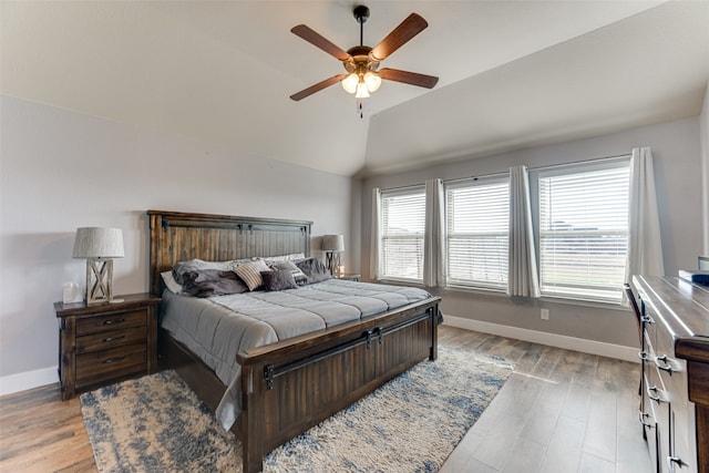 bedroom with ceiling fan, vaulted ceiling, and light wood-type flooring