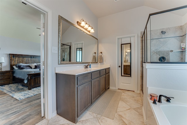 bathroom featuring tile patterned floors, vanity, independent shower and bath, and vaulted ceiling