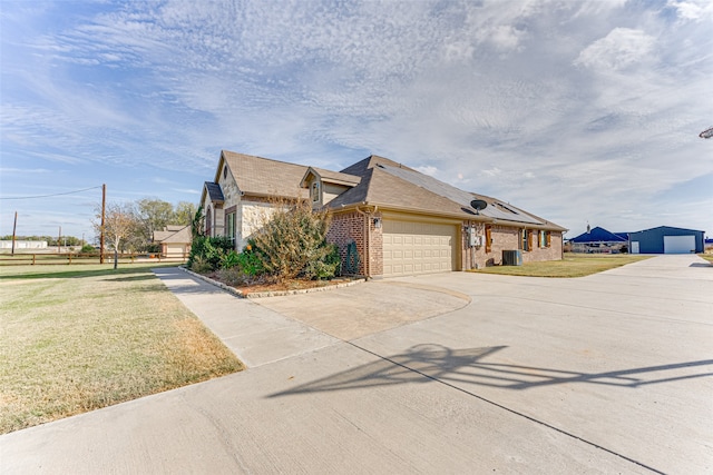 view of front of house with a garage, central AC, and a front yard