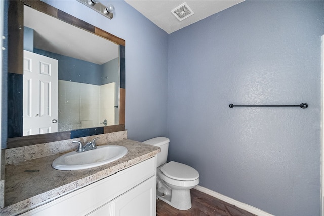 bathroom featuring a shower, hardwood / wood-style floors, vanity, and toilet