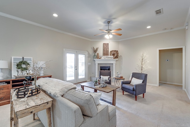 living room with ceiling fan, french doors, light colored carpet, a fireplace, and ornamental molding