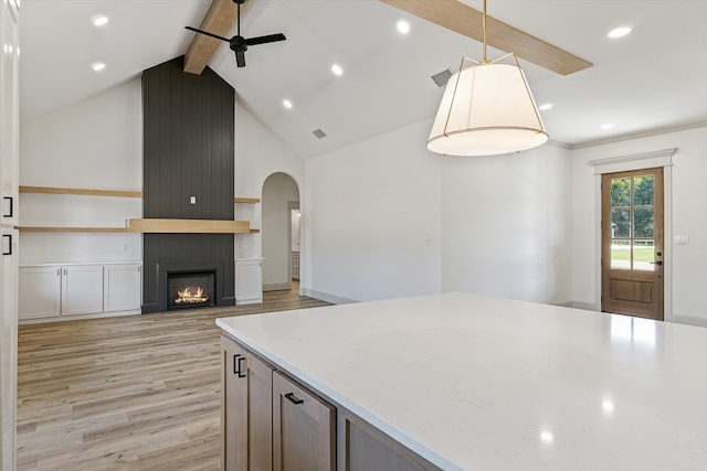 kitchen featuring light stone countertops, light wood-type flooring, a large fireplace, ceiling fan, and hanging light fixtures