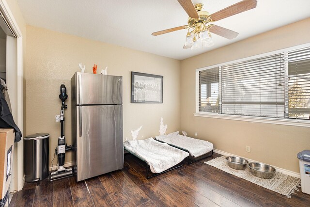 bedroom featuring ceiling fan, dark hardwood / wood-style flooring, and stainless steel refrigerator