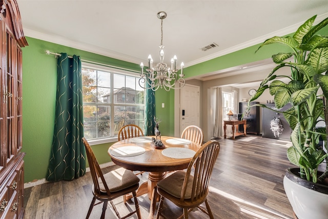 dining space with wood-type flooring, crown molding, and a notable chandelier