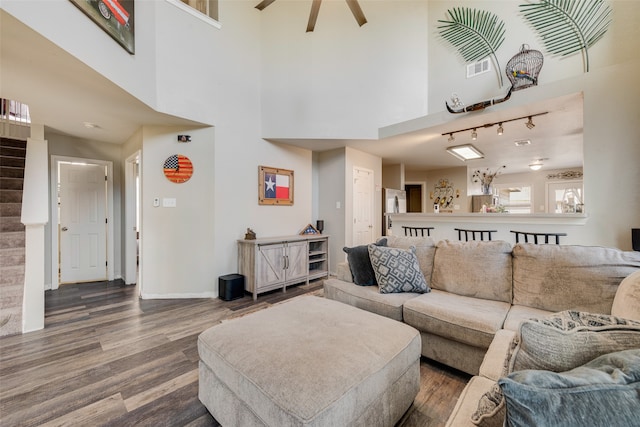 living room featuring hardwood / wood-style flooring, a towering ceiling, and rail lighting