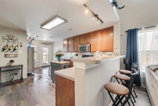 kitchen with a breakfast bar area, kitchen peninsula, backsplash, and wood-type flooring