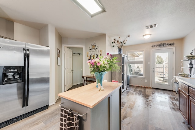 kitchen with wooden counters, stainless steel fridge, light wood-type flooring, a textured ceiling, and dark brown cabinets