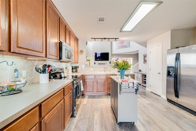 kitchen with sink, decorative backsplash, a kitchen island, light hardwood / wood-style floors, and stainless steel appliances