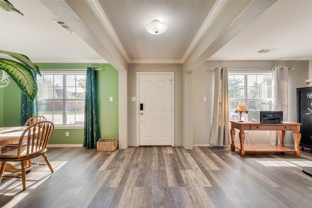 foyer featuring wood-type flooring, a textured ceiling, crown molding, and a healthy amount of sunlight