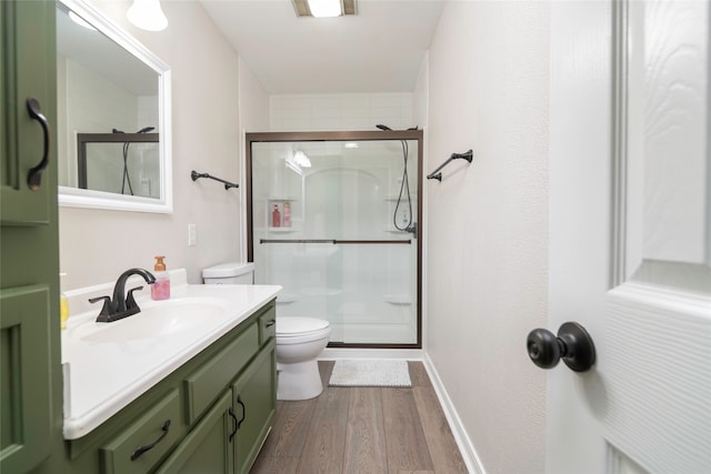 bathroom featuring vanity, toilet, wood-type flooring, and a shower with door