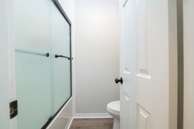 bathroom featuring shower / bath combination with glass door, hardwood / wood-style flooring, and toilet