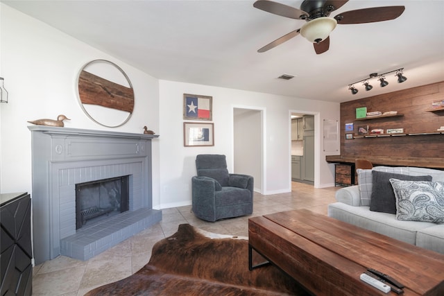 living room featuring ceiling fan, light tile patterned flooring, track lighting, and a brick fireplace