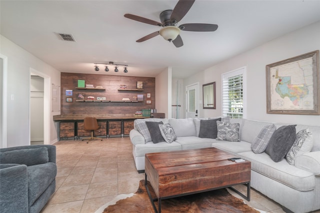 tiled living room featuring ceiling fan and wooden walls