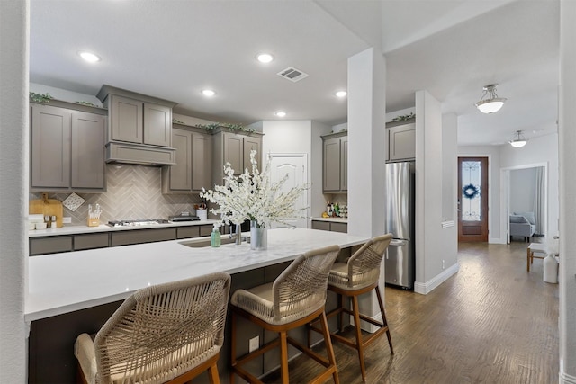 kitchen featuring dark hardwood / wood-style flooring, decorative backsplash, a breakfast bar area, and appliances with stainless steel finishes