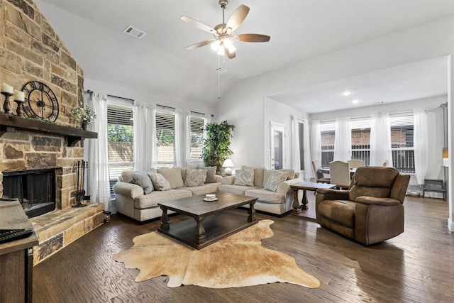 living room with ceiling fan, lofted ceiling, a stone fireplace, and dark hardwood / wood-style flooring