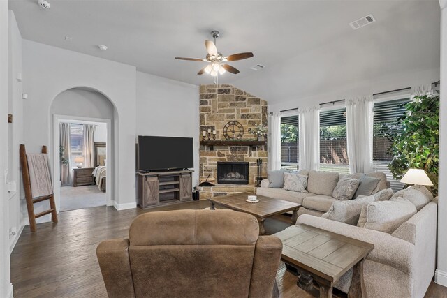 living room with ceiling fan, lofted ceiling, a stone fireplace, and dark hardwood / wood-style flooring