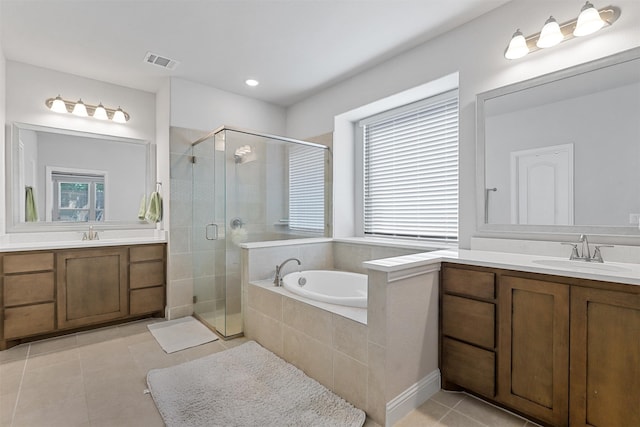 bathroom with plus walk in shower, a healthy amount of sunlight, tile patterned floors, and vanity