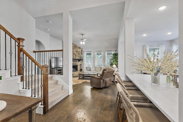 living room with ceiling fan, a fireplace, dark hardwood / wood-style floors, and vaulted ceiling