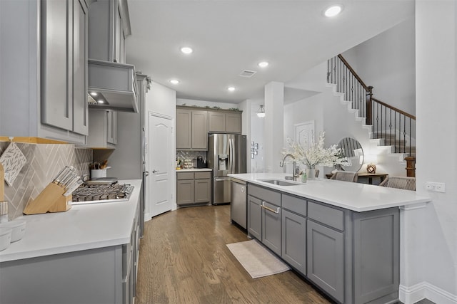 kitchen with sink, gray cabinets, appliances with stainless steel finishes, tasteful backsplash, and dark hardwood / wood-style flooring