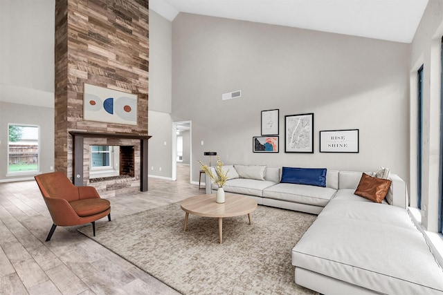 living room with light hardwood / wood-style floors, a fireplace, and high vaulted ceiling