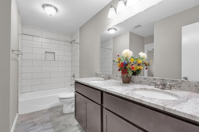 full bathroom featuring vanity, wood-type flooring, tiled shower / bath combo, and toilet