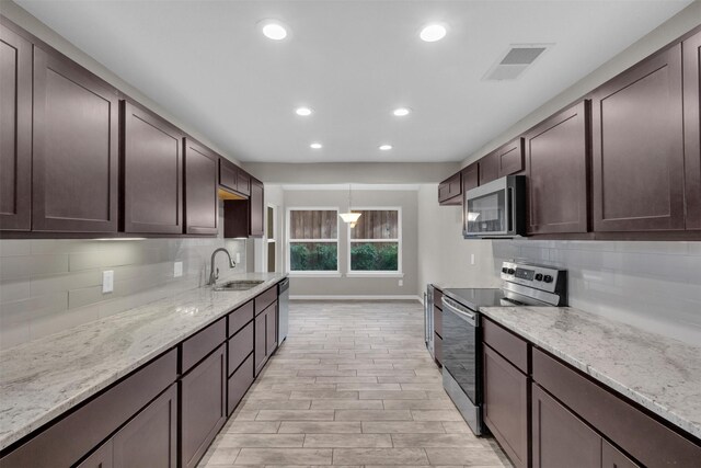 kitchen with pendant lighting, sink, light hardwood / wood-style flooring, appliances with stainless steel finishes, and dark brown cabinetry