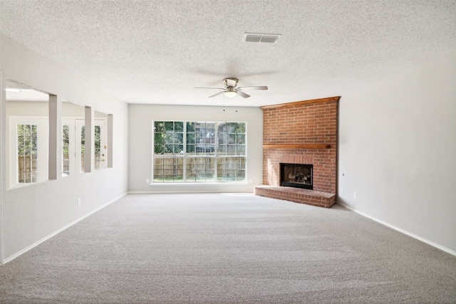 unfurnished living room featuring carpet, ceiling fan, a textured ceiling, and a brick fireplace